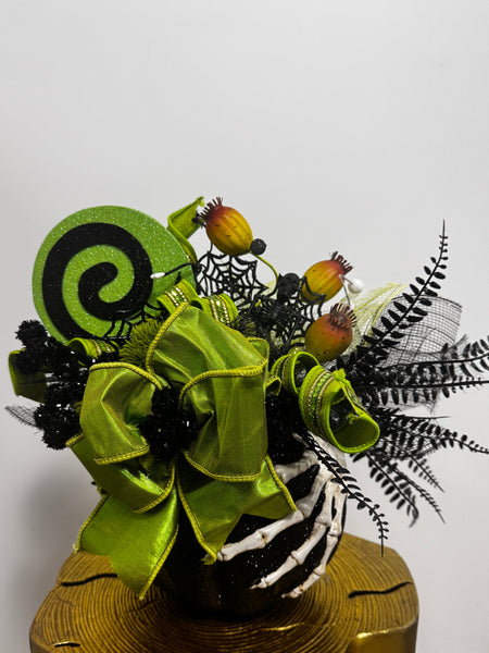 Decorative Halloween flower arrangement with green ribbons and black accents on a white background