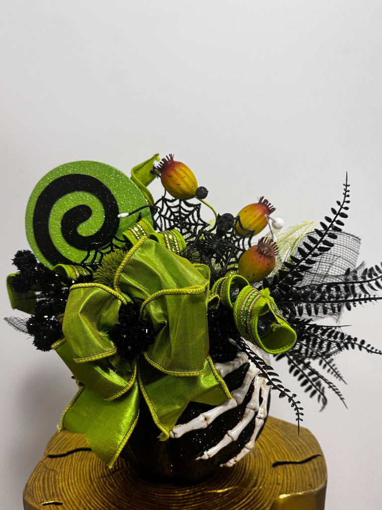 Decorative Halloween flower arrangement with green ribbons and black accents on a white background