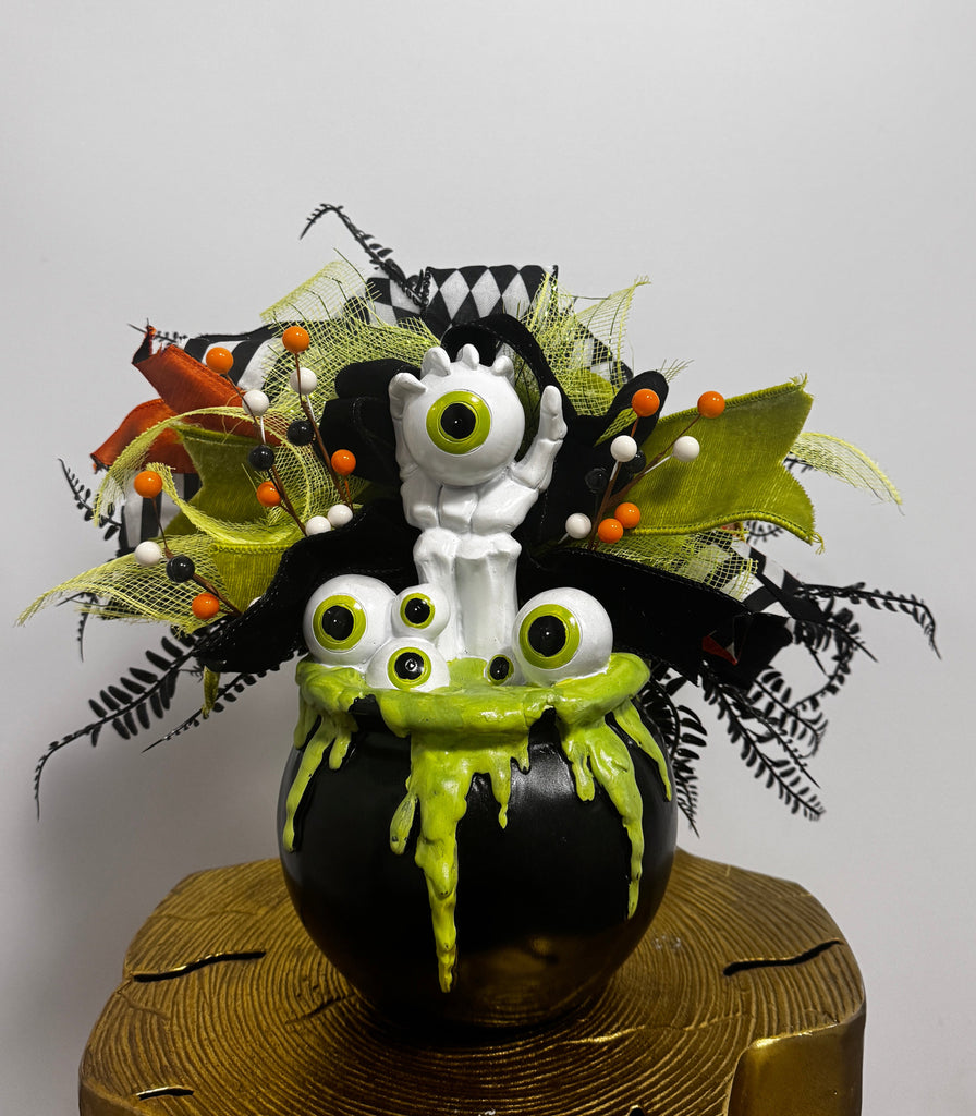 Decorative Halloween-themed topiary with green and black leaves on a white background