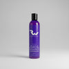 Purple shampoo bottle with black cap on a wooden surface in a bathroom setting